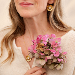 3.	Collier soleil Garance aux nuances pêche et dorées, posé sur un tissu rose clair.