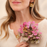 3.	Collier soleil Garance aux nuances pêche et dorées, posé sur un tissu rose clair.