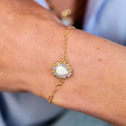 3.	Bracelet doré en tanzanite posé sur un fond rose poudré.